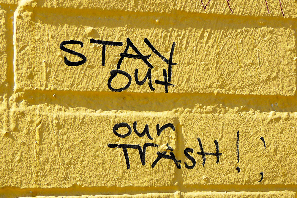 Tagging on wall reads 'Stay out our trash'