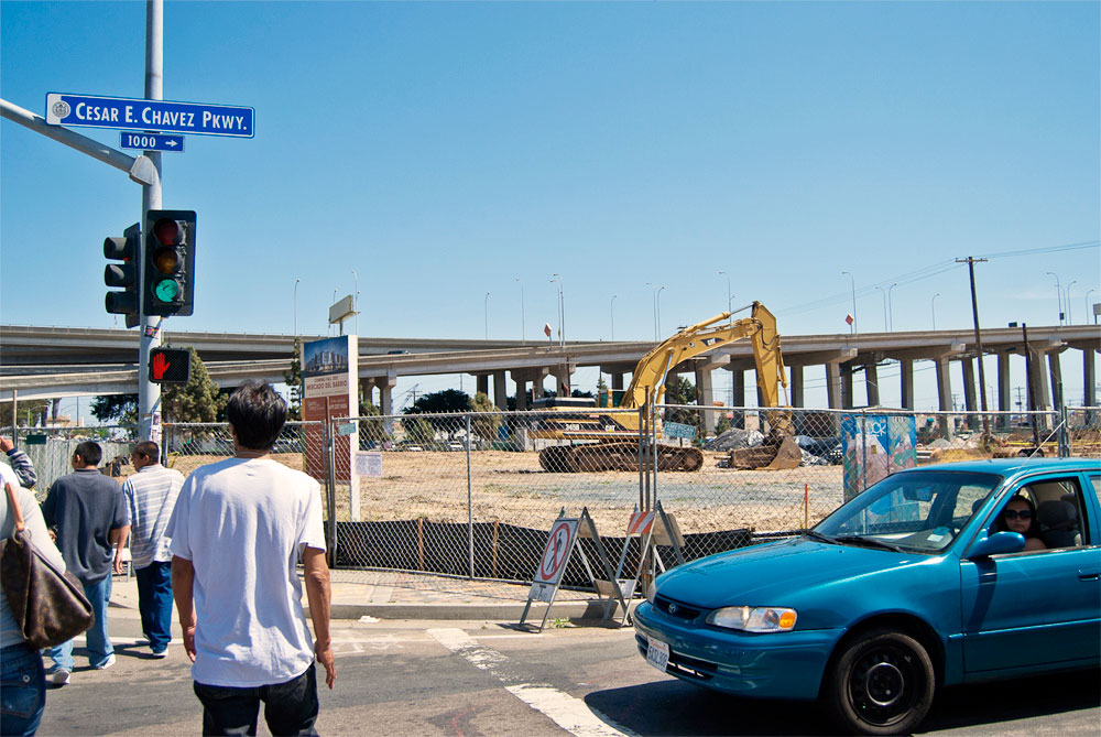 Image of people walking towards the Chicano Park Day celebration with construction of El Mercado in background.